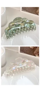 Macro shot of large French hollow hair claws in gray-green and iridescent pearly white marble