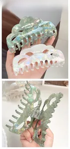 Close-up of large pearlescent acetate hair claws in mint green and white with metal spring