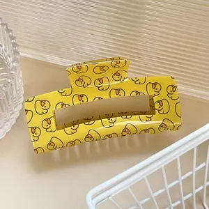 Détail d'une pince à cheveux rectangulaire jaune avec motif de canard de dessin animé