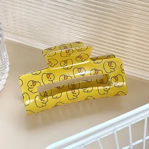 Détail d'une grande pince à cheveux jaune avec motif canard sur fond esthétique clair