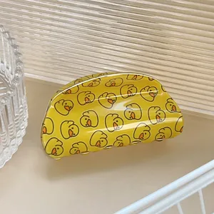 Détail d'une pince à cheveux jaune semi-circulaire avec motifs de canards mignons