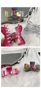 Detail view of large acetate bow hair claws in rainbow, pink marble, and transparent grey