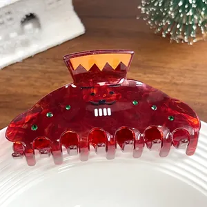 Détail d'une pince à cheveux bordeaux marbrée avec strass et motif de visage rigolo