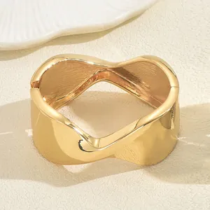 Close-up of gold-plated wide cuff bracelet with modern irregular wavy texture design