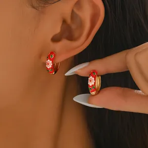 Gold huggie earrings with red enamel and white flower pattern for a retro aesthetic