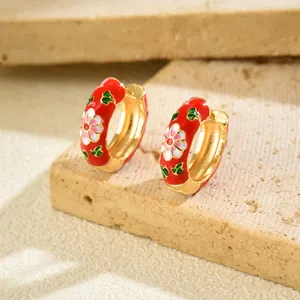 Macro shot of gold-plated flower earrings with red enamel and intricate petal details