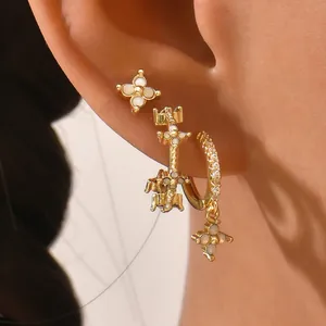 Macro shot of gold geometric earrings set with white gems worn on ear for styling