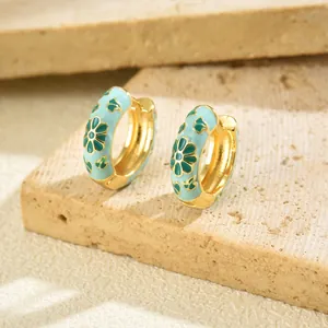 Detailed shot of light blue enamel flower earrings with daisy motif on a stone background