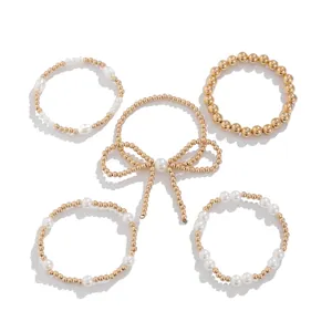 Set de 5 pulseras de cuentas doradas con perlas blancas y diseño de lazo tejido elegante