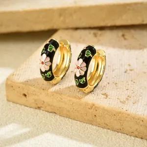 Detail of gold hoop earrings with black enamel and pink daisy floral pattern
