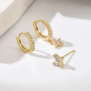 Golden geometric earring set featuring floral studs and crystal-inlaid hoops with charms