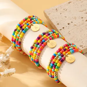 Drei bunte Perlenarmbänder mit goldenen Buchstaben-Anhängern A, R, M im Boho-Stil