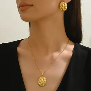 Parure de bijoux dorés avec collier et boucles d'oreilles sur modèle portant une robe noire