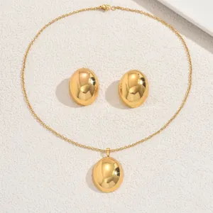 Gros plan détaillé de la parure collier pendentif ovale doré poli et boucles d'oreilles