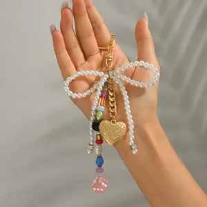 Handmade pearl bow keychain with golden heart pendant and colorful beads on metal chain