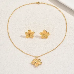 Détail du coffret de bijoux dorés avec collier floral et boucles d'oreilles clous