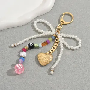 Handmade pearl bow keychain with heart pendant and colorful beads on a gold lobster clasp