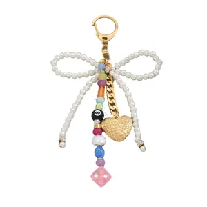 Handmade pearl bow keychain with colorful beads and golden heart charm on white background