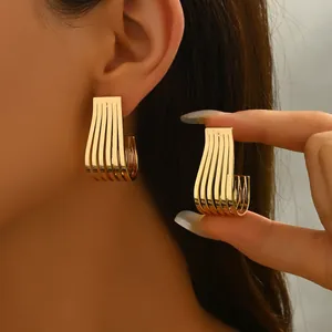 Elegant gold U-shaped ribbed earrings with vertical striped texture shown on a model