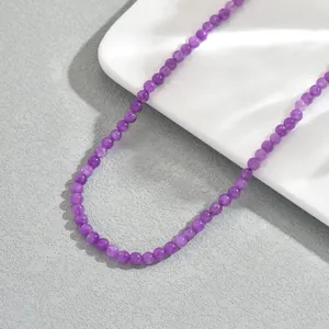 Dettaglio della collana di perline di ametista viola su vassoio in ceramica bianco