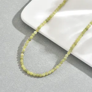 Macro di una collana di perle in pietra naturale verde chiaro su un vassoio bianco