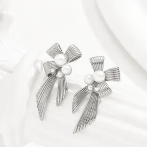 Elegant silver bow earrings with geometric pearl inlay on minimalist display