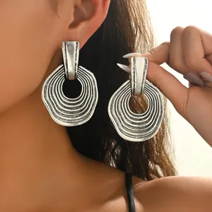 Détail de boucles d'oreilles argentées vintage avec texture ondulée sur un mannequin
