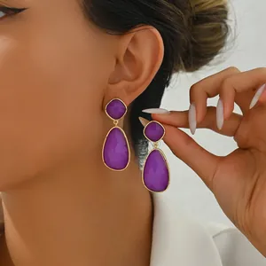 Close-up of elegant purple teardrop earrings on model showing stylish golden metal trim
