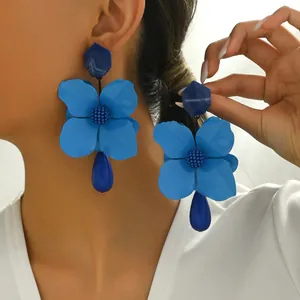 Blue floral drop earrings with geometric studs and teardrop resin dangles on model