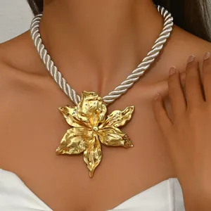 Statement necklace featuring a large textured gold flower pendant on a bold silver cord