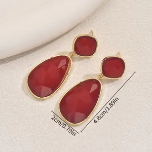 Elegant geometric gold-plated drop earrings featuring faceted burgundy red gemstones