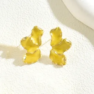 Dettaglio macro degli orecchini a quadrifoglio in smalto giallo con bordi dorati lucidi