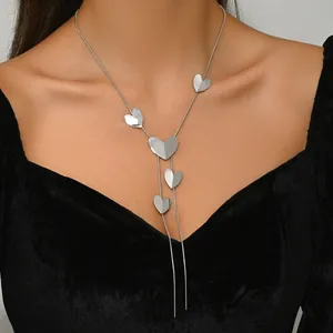 Detailed view of silver Y-shaped tassel necklace with polished heart charms on model