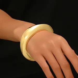 Brazalete ancho de oro pulido con un diseño geométrico minimalista grueso en la muñeca