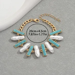 Goldenes geometrisches Armband mit Türkissteinen und Barockperlen auf grauem Grund