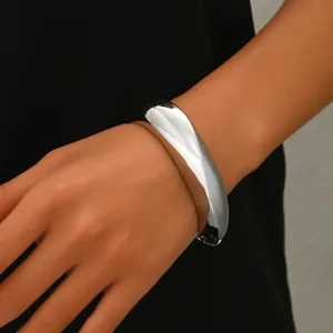 Detalle de brazalete plateado ondulado con acabado de espejo en la muñeca de la modelo