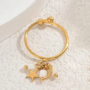 Detailansicht verstellbarer Goldring mit Stern-, Mond- und Perlenanhängern auf Stein
