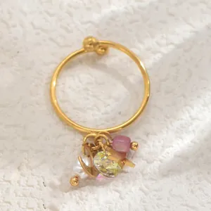 Detailansicht eines Goldrings mit Mond-Stern-Anhängern, rosa Perle und gelbem Kristall
