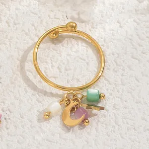 Nahaufnahme eines goldenen Rings mit Mond Stern Anhängern und bunten Perlenakzenten