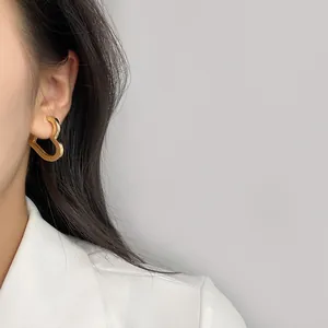 Eleganti orecchini a cerchio a forma di cuore in metallo dorato indossati da una modella