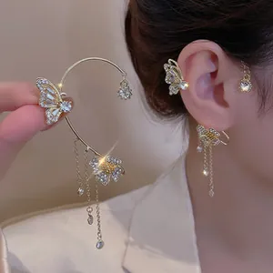 Close-up of golden butterfly ear cuff with sparkling rhinestones and long chain tassels