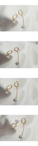 Detailed view of asymmetric gold ear cuffs with pearls on elegant white silk fabric