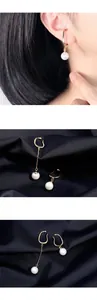 Detail of elegant gold ear cuffs with lustrous white pearls on black silk background