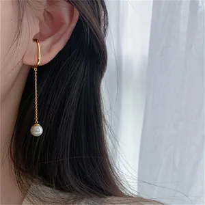 Detailed view of elegant gold ear cuff with long chain and white pearl drop accessory