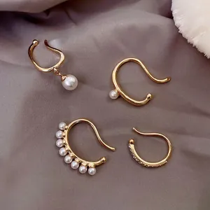 Set of 4 gold-finish pearl ear cuffs with crystal accents on purple silk background