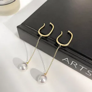 Elegant gold chain ear cuff with white pearls for non-pierced ears shown on a book