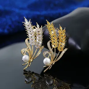 Dettaglio di spille a spiga di grano con placcatura in oro, zirconi brillanti e perle bianche