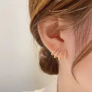 Macro detail of four-row gold plated stud earrings with zircon stones on model's ear