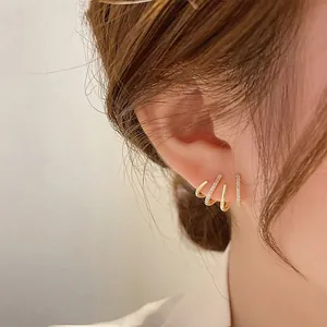 Nahaufnahme der goldenen mehrlagigen Krallen-Ohrstecker mit Zirkonia-Besatz am Ohr
