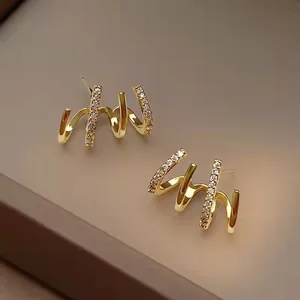 Vergoldete Spiral-Ohrstecker mit Zirkonia-Besatz und vier Krappen auf Lederhintergrund